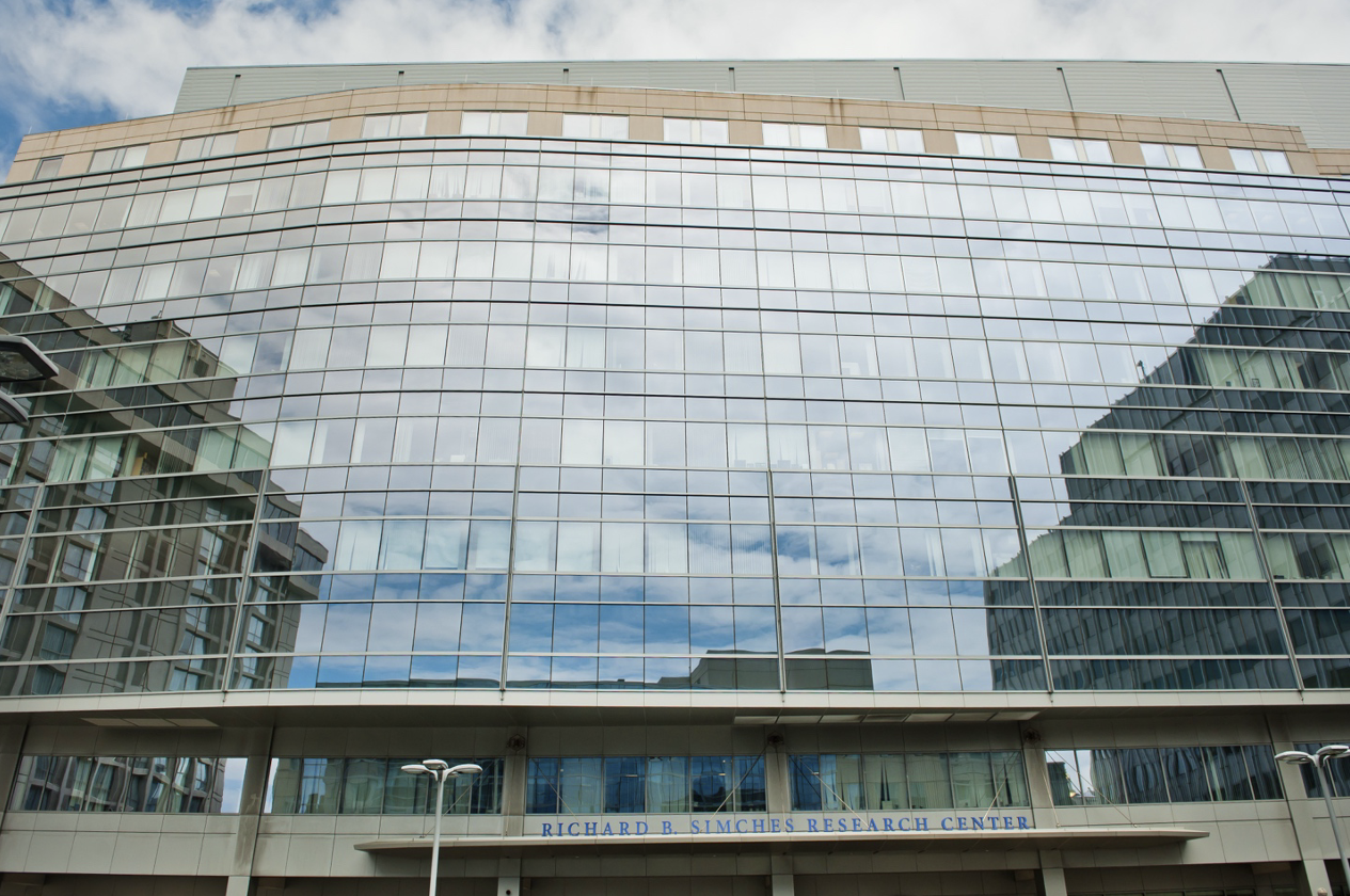 ull view of the Richard B. Simches Research Center with glass exterior reflecting the sky.